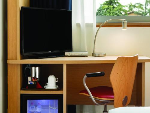 a desk with a television and a chair in a room at Mitico Hotel & Natural Spa in Bologna