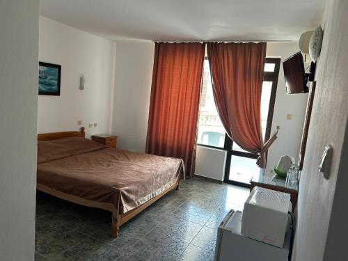a bedroom with a bed and a large window at КЪЩА"Перла" in Ravda
