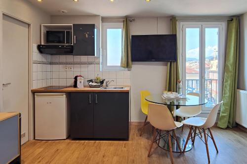 a kitchen with a table and a table and chairs at Aparthotel AMMI Nice Massena - ex Ajoupa in Nice