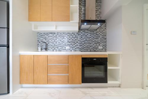a kitchen with wooden cabinets and a black oven at Andaman Villa 15 minutes from Bangtao Beach in Phuket Town