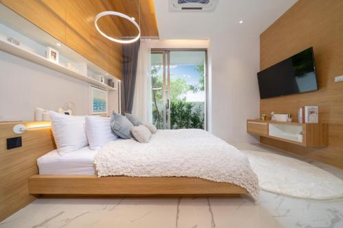 a bedroom with a bed with a tv and a window at Andaman Villa 15 minutes from Bangtao Beach in Phuket Town