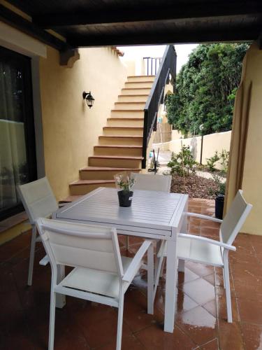 a white table and chairs on a patio with stairs at Casa Logos Stintino - Private pool in Stintino