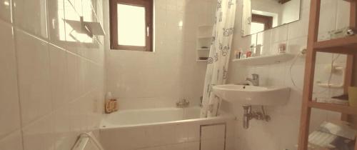 a white bathroom with a sink and a tub and a toilet at la maison de westende in Middelkerke