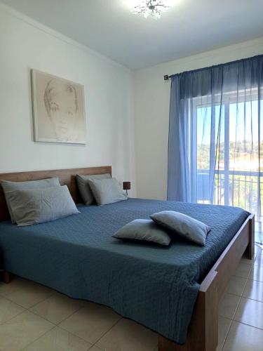 a bedroom with a bed with blue sheets and a window at Tavira sweet home in Tavira