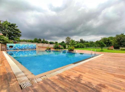 a large swimming pool with a wooden deck at Serene 43, Karjat 3 BHK Villa, Wifi, Plunge Pool in Karjat