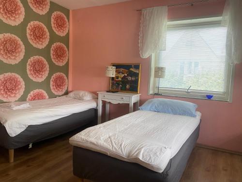 two beds in a room with pink walls and a window at Anita in Kristianstad