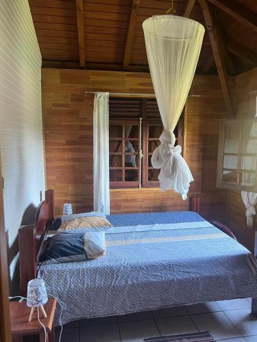 a bedroom with a bed with a curtain and a window at Les Alpinias in Sainte-Anne