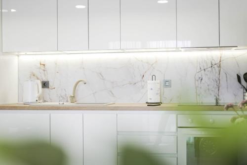 a white kitchen with white cabinets and marble counter tops at Apartman Marijana in Bjelovar