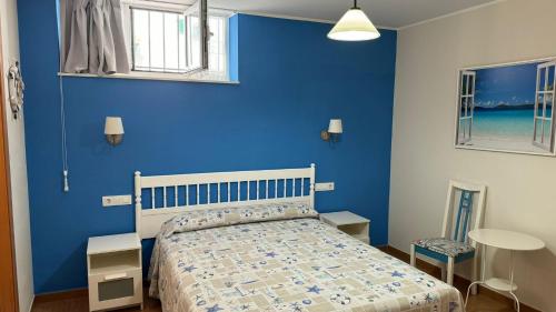 a blue bedroom with a bed and a blue wall at Hotel Las Terrazas in Tazones