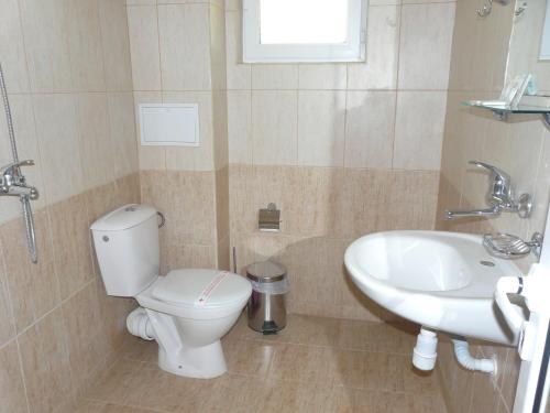 a bathroom with a toilet and a sink at Семеен Хотел Детелини in Primorsko