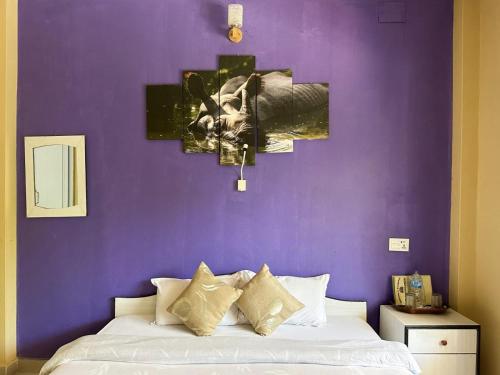 a bedroom with a purple wall with a bed at Hotel Rhinoceros-Homestay in Sauraha