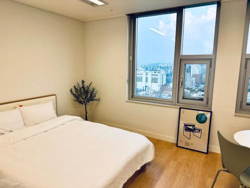 a bedroom with a white bed and a large window at "GRAND OPENED" Maxtyle Guesthouse Dongdaemun in Seoul