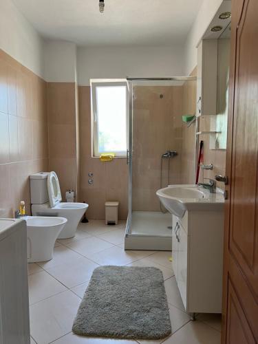 a bathroom with a shower and a toilet and a sink at The White Villa in Hamallë