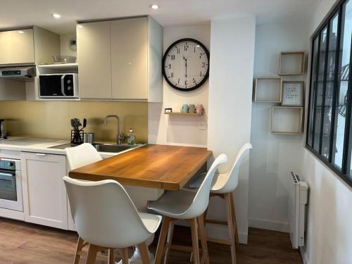 une cuisine avec une table en bois et une horloge au mur dans l'établissement Appartement Douillet Central - Parking Inclus, à Manosque