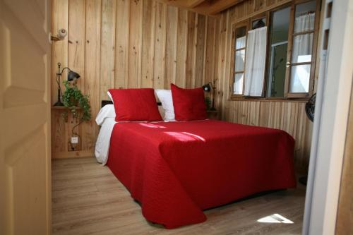 1 dormitorio con 1 cama grande con sábanas rojas en La Cabanote, en Biscarrosse