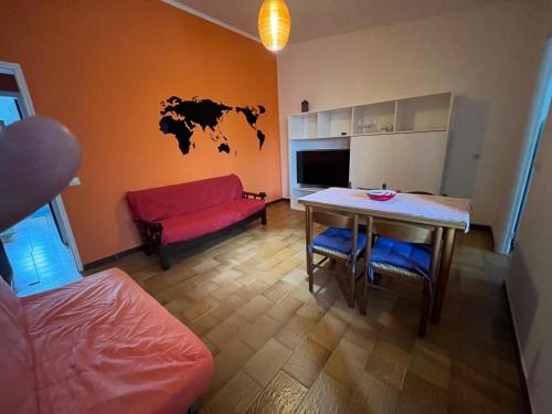 Una sala de estar con una mesa y un sofá rojo. en Appartamento Navarra, en Santa Maria Navarrese