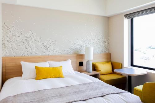 a bedroom with a bed and a yellow chair at Hotel Terrace the Garden Mito in Mito