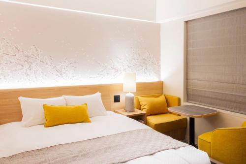a bedroom with a bed and a yellow chair at Hotel Terrace the Garden Mito in Mito