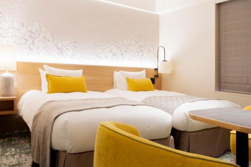two beds in a hotel room with yellow pillows at Hotel Terrace the Garden Mito in Mito