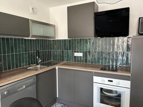 Il comprend une cuisine avec un évier et une télévision murale. dans l'établissement Appartement cosy avec 1 place de parking privée, à Albertville