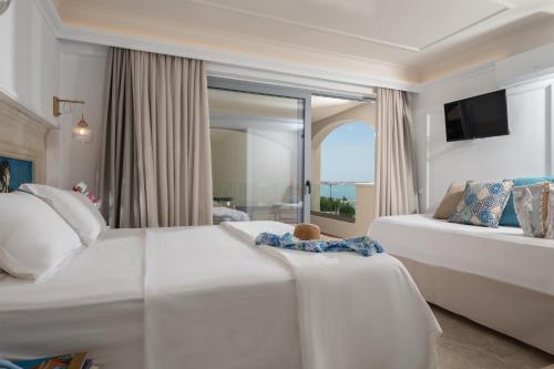 a hotel room with two beds and a couch at Parthenis Beach, Suites by the Sea in Malia