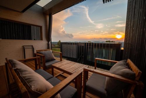 a balcony with chairs and a table and a sunset at Stock & Stein Lodges in Bad Gleichenberg