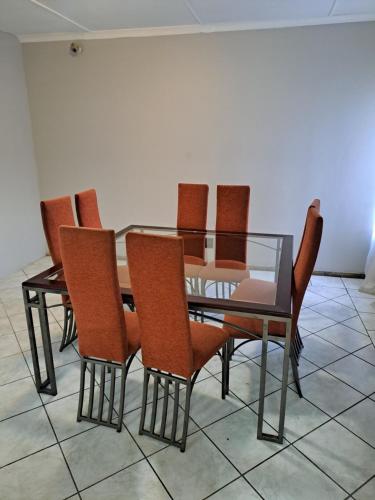 a dining room with a glass table and chairs at Randhart guesthouse in Alberton