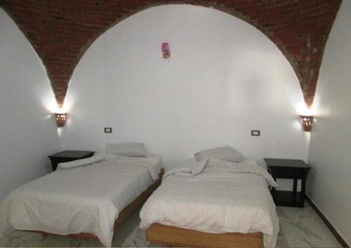 two beds in a room with two lights on the wall at Lucky Seven in Luxor