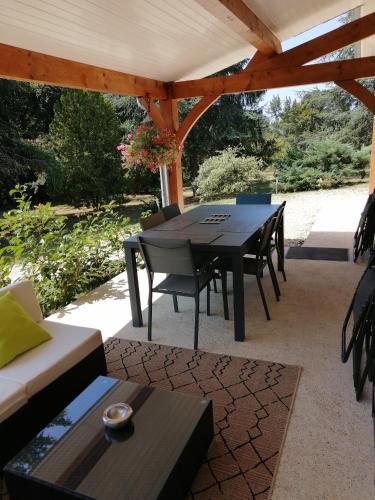 un patio avec une table et des chaises sous une pergola dans l'établissement L'Esquiròu du Sécadou, à Castels