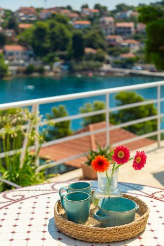 a table with plates and cups and flowers on a balcony at Holiday Home Dora in Splitska