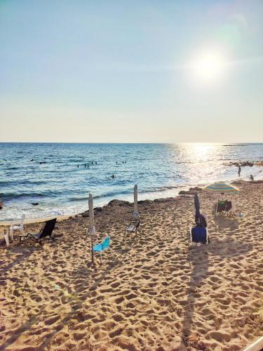 a beach with chairs and umbrellas and the ocean at Beach front house at Agios Ilias Pyrgos Near Ancient Olympia in Áyios Ilías