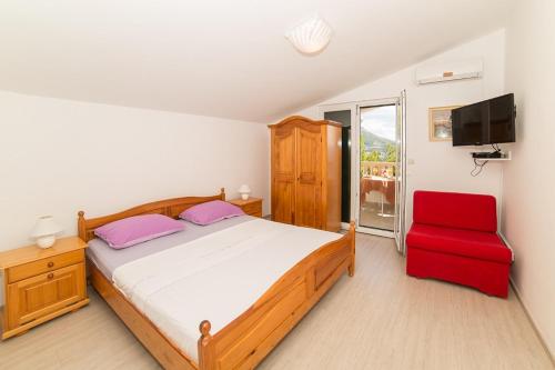 a bedroom with a bed and a red chair at Villa Nada in Duće