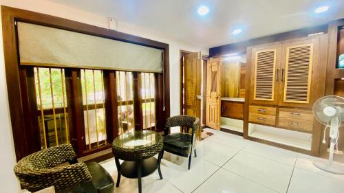 a room with a table and chairs and windows at Willo stays The Metro Landsend Beach Resorts in Kannur