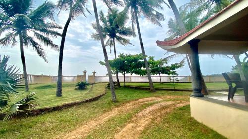 a view of a yard with palm trees and a house at Willo stays The Metro Landsend Beach Resorts in Kannur
