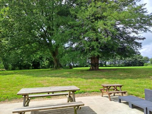 two picnic tables and benches in a park at Gîte détente Domaine de Helles -Spa Privatif et Sauna in Poullaouen
