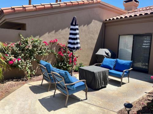 a patio with two chairs and a table and an umbrella at Relax in Palm Valley Comfort in Palm Desert