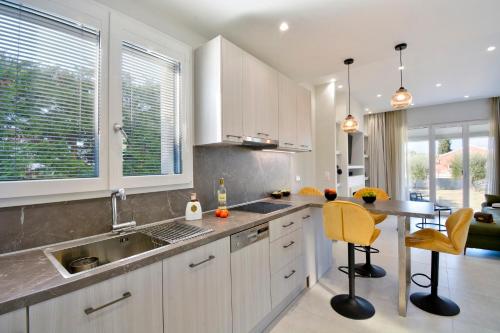 a kitchen with a sink and a table with yellow chairs at Villa Verde, Kobitsi Corfu in Corfu