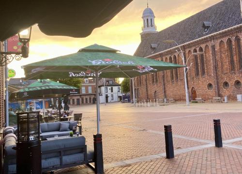 a large green umbrella on a street in front of a building at Hotel Restaurant 't Ronde Loegh in Winschoten