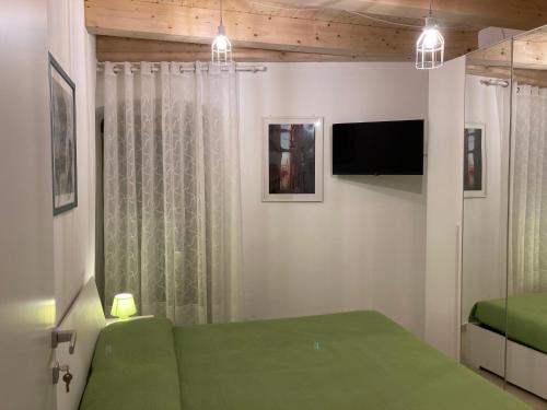 a bedroom with a green bed and a flat screen tv at Casa Gaia, La Casa Sui Tetti in Isolabona