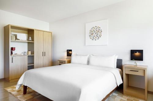 a white bedroom with a large white bed and cabinets at NOUN Hotel, Norman, a Tribute Portfolio Hotel in Norman
