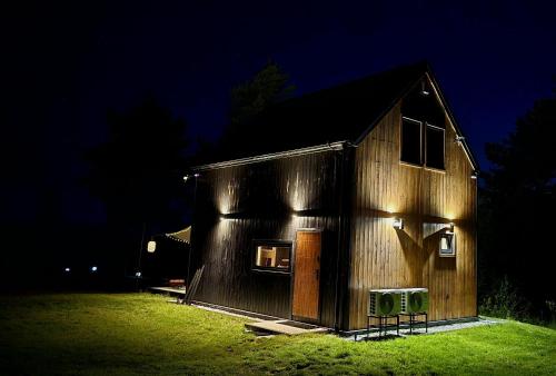 a barn with lights on the side of it at night at Mazurskie Wzgórze Nad Jeziorem Isąg in Pelnik