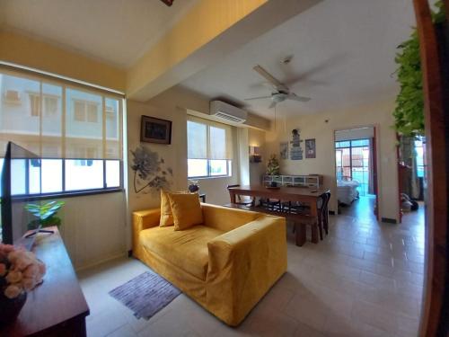 un salon avec un canapé jaune et une table dans l'établissement King Bed 2BR European Style City Center in Davao City Philippines, à Davao