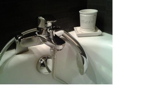 a bathroom sink with a faucet and a cup at Hôtel du Golf Saint Lazare in Limoges