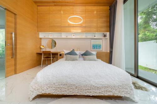 a bedroom with a large white bed and a desk at Andaman Villa 15 minutes from Bangtao Beach in Phuket Town