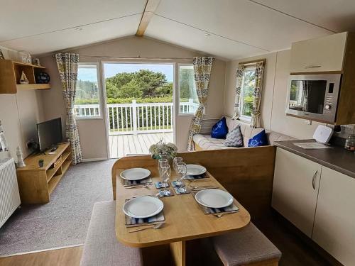 a kitchen and living room with a table in a room at Dog Friendly 8 Berth Static Caravan Newquay in Newquay