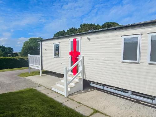 a white caravan with a red bow on the door at Dog Friendly 8 Berth Static Caravan Newquay in Newquay