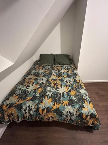 - un lit avec une couette à fleurs dans l'établissement Natur 'Appart entre forêt et rivière, à LʼHuisserie