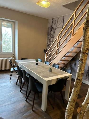 une table et des chaises dans une pièce avec un escalier dans l'établissement Natur 'Appart entre forêt et rivière, à LʼHuisserie