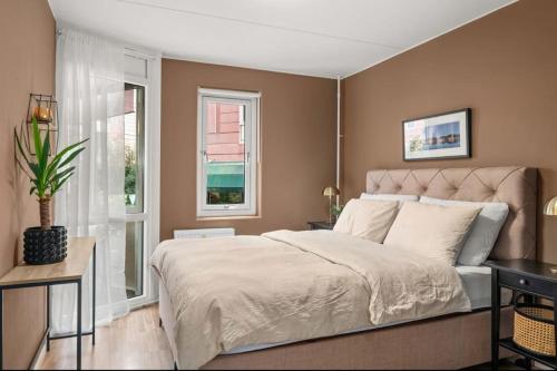a bedroom with a large bed and two windows at Sentral & Cozy apartment in Oslo