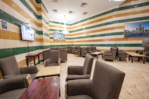 a waiting room with chairs and tables and a tv at فندق الأحباب الكبرى الفندقية ٢ in Makkah